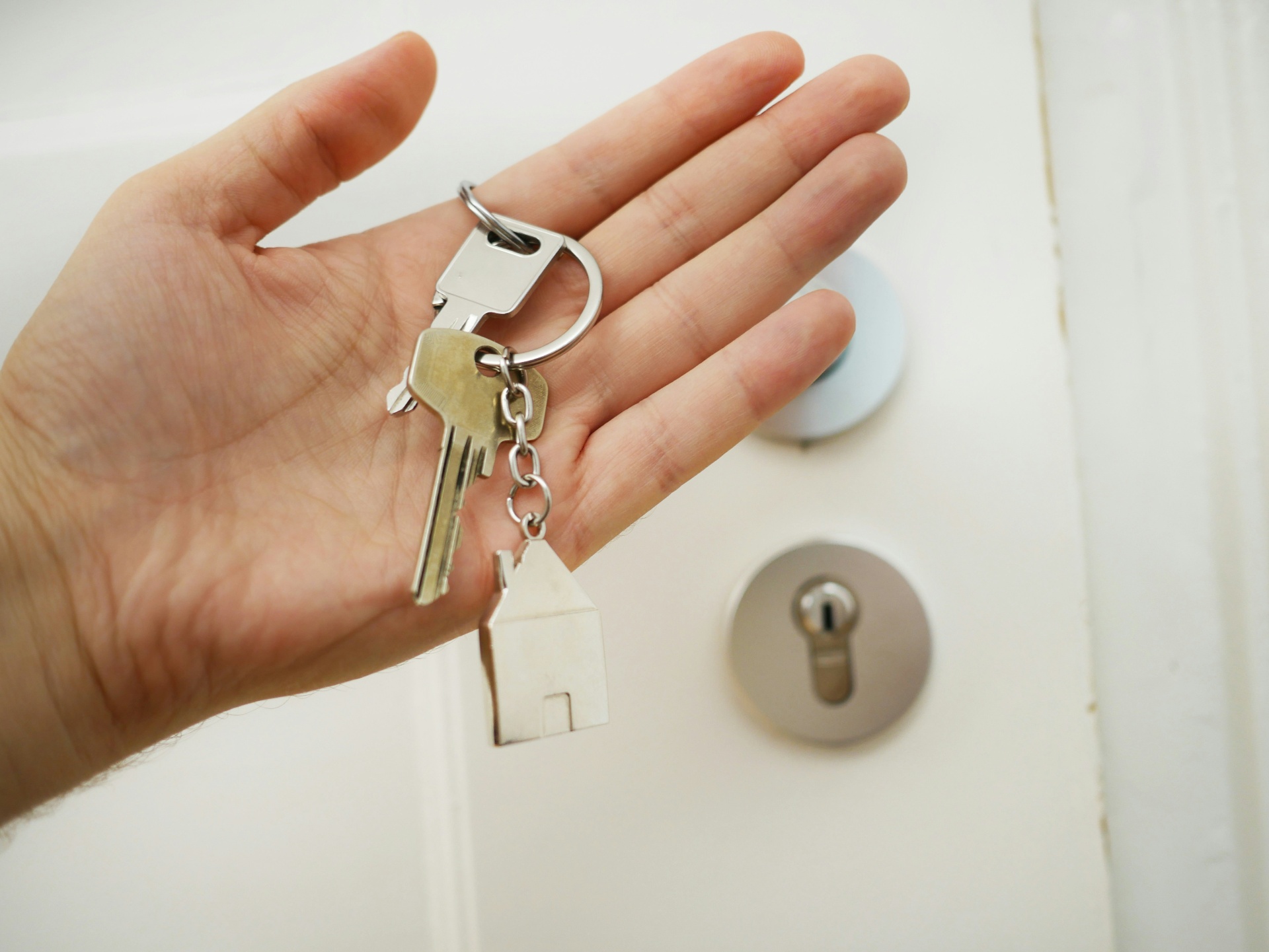 Mano sosteniendo llaves con llavero en forma de casa
